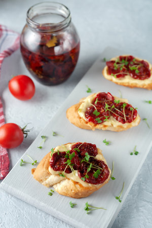 Sandwich with sun-dried tomatoes, homemade mayonnaise and micro greens, served on a board on a gray backgroundの写真素材