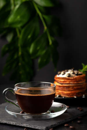 On the table is a cup of freshly brewed fragrant coffee with homemade pancakes with fresh berriesの写真素材