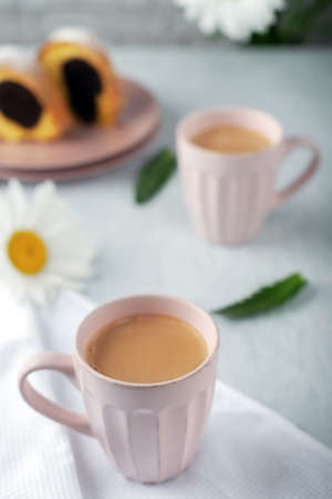 Two cups of freshly made coffee with cream with cupcake and chamomile flowersの写真素材