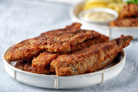 Fried fish with green peas, lemon and fried potatoes