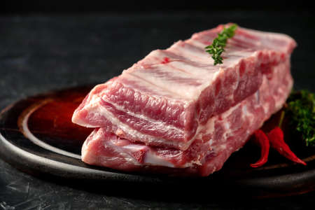 Raw pork ribs with spices and thyme on a dark wooden backgroundの写真素材