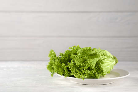 Dietary nutrition. Fresh lettuce leaves on a platter on a wooden background.の写真素材