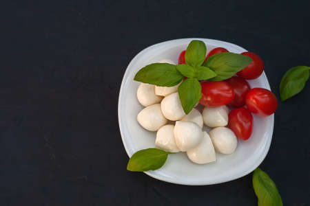 Mini mozzarella with tomatoes and basil on a plateの写真素材