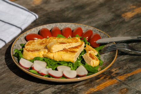 European breakfast. A light breakfast of French omelet with radishes, spinach tomatoes and arugula.