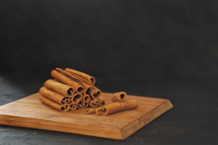 Fragrant cinnamon sticks on a wooden board on a black backgroundの写真素材
