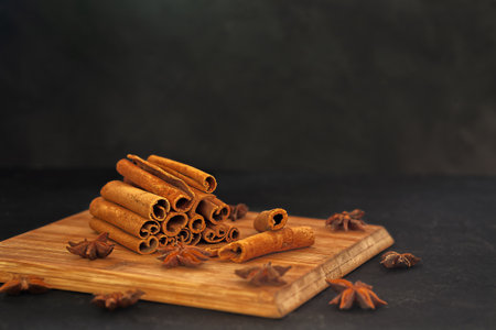 On a black background, fragrant cinnamon sticks with anise on a wooden boardの写真素材