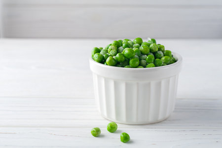 Freshly frozen green peas on a white wooden backgroundの写真素材