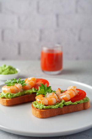 Healthy snack or shrimp bruschetta with avocado and bread. Fried shrimp and mashed avocado on toasted breadの写真素材