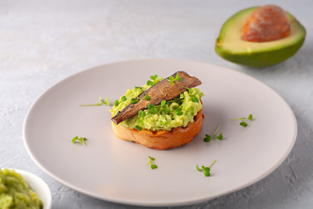 Sandwiches with sprats on toasted slices of bread. Sandwich with smoked sprat - fish, avocado and microgreens.の写真素材