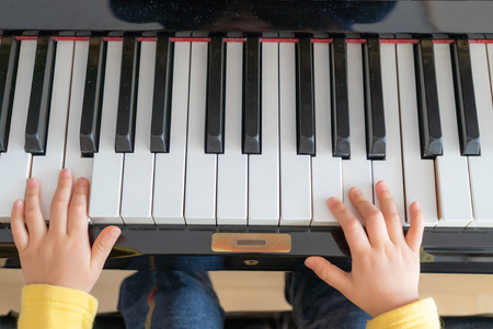children's hands on the keys of the piano