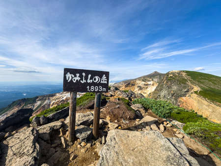 Tokachi-dake and Kamihorokamettoku ridgeline viewed from the summit of Mount Kamifurano in the Daisetsuzan Range, Hokkaido, Japan, with rugged volcanic terrain and clear summer skyの写真素材