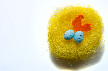 Artificial easter nest with two eggs and cock isolated