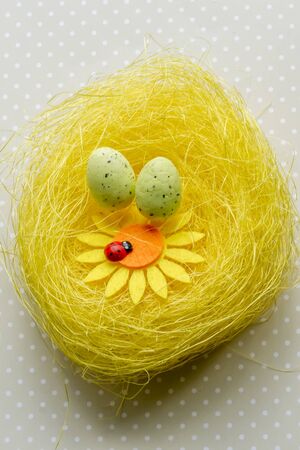 Artificial easter nest with two eggs, flower and ladybugの写真素材