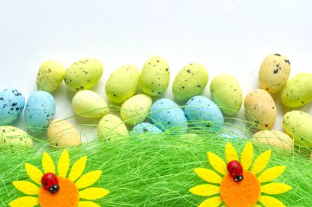 Artificial grass with colored eggs and two sunflowers backgroundの写真素材