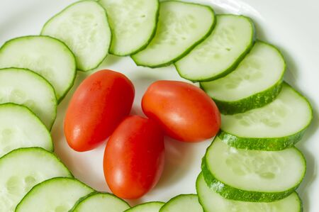 cucumbers and cherry tomatoes on a white plateの写真素材