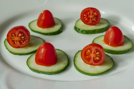cucumbers and cherry tomatoes on a white plateの写真素材