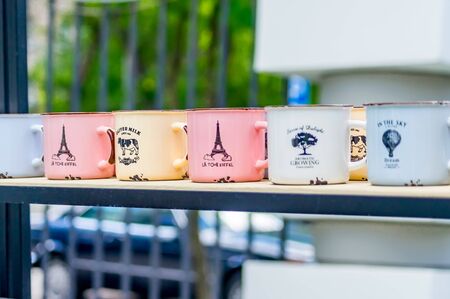 multicolored enamel cups standing in a row on a shelf. Cups with decoration and letteringの写真素材