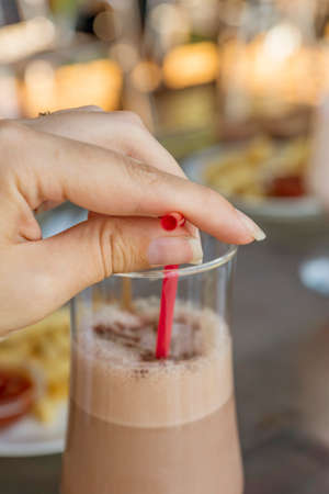 chocolate milk shake cocktail in woman hand on the open terrace summer time. Toned.