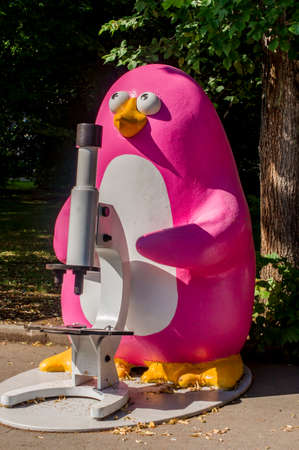 colorful statue of penguin with microscope in city garden の写真素材