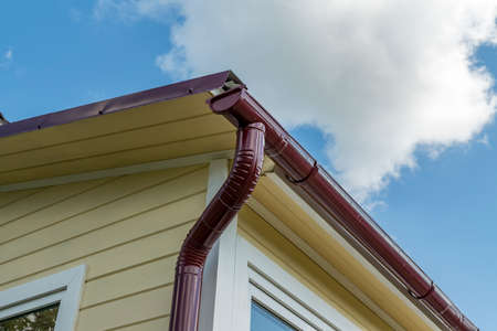 Corner of the house with gutter on a background of blue sky