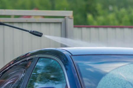 man washing his car under high pressure water outdoorsの写真素材