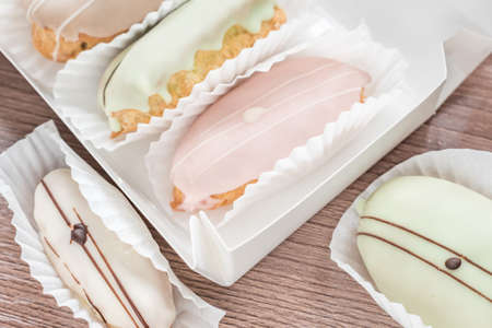 french eclairs in box on wooden table closeup