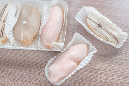 french eclairs in box on wooden table closeup