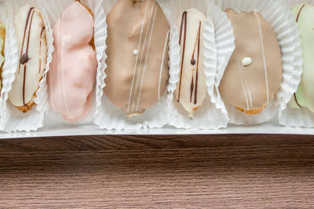 french eclairs in box on wooden table closeup