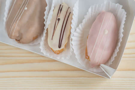 closeup of french eclairs in box on wooden background