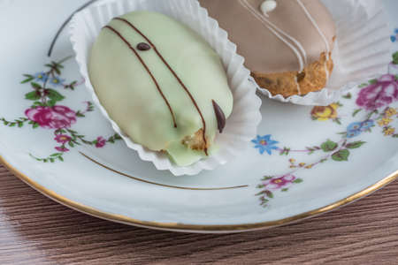 french eclairs on colorful porcelain plate on wooden table.