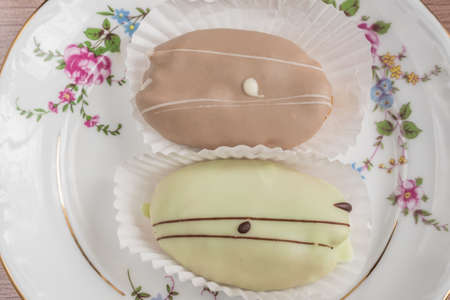 french eclairs on colorful porcelain plate on wooden table. top view