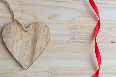 wooden heart on wooden background with red ribbonの写真素材