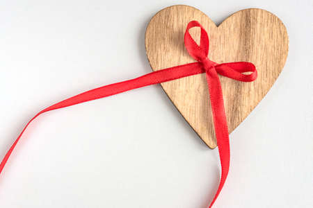 wooden heart with red ribbon bow on white backgroundの写真素材