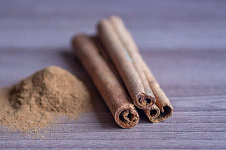 cinnamon sticks and powder on wooden table. toned