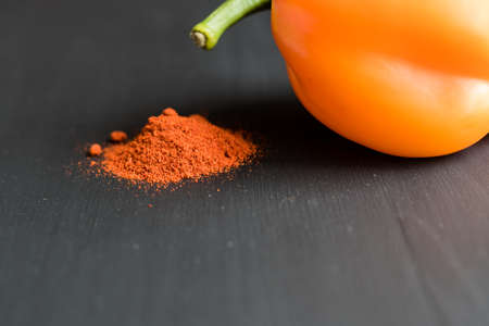 orange bell pepper and paprika powder on black background, copy space for your textの写真素材