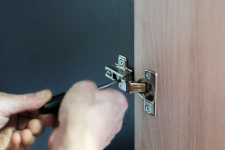 Closeup of worker's hands fitting wardrobe hinge doors in closetの写真素材