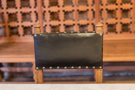 black leather back of chair on carved wooden backgroundの写真素材