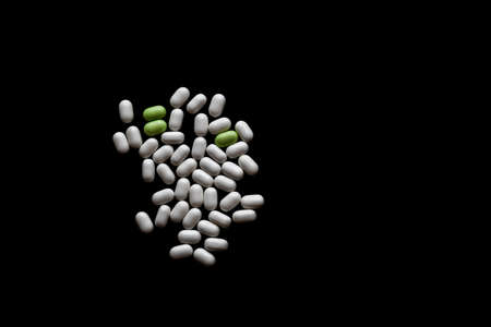 white and green pills On black wooden background with copy spaceの写真素材