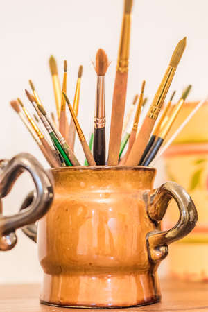 Brushes of the artist in clay pitcher  on wooden shelfの写真素材