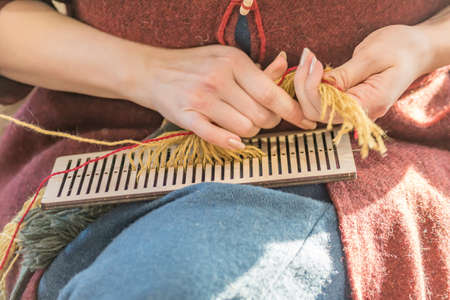 woman in traditional russian clothes weaves a spindleの写真素材