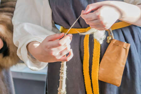 woman in traditional russian clothes weaves a spindle
