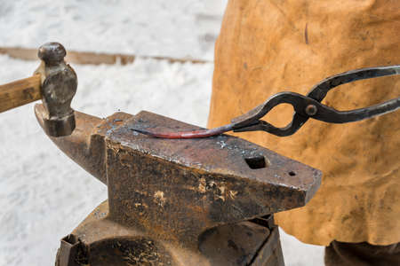 blacksmith manually forging the molten metal on the anvil outdoors
