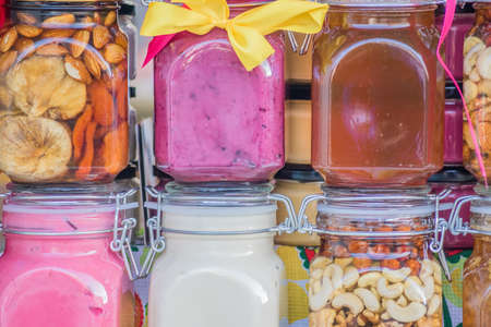 Glass jars with different sorts of honey on red backgroundの写真素材