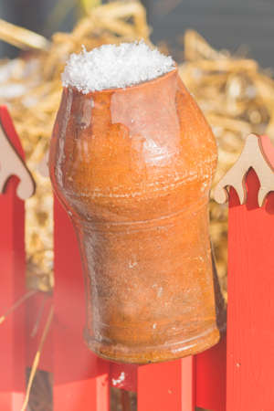 Clay vintage traditional pot on the fence covered with snowの写真素材