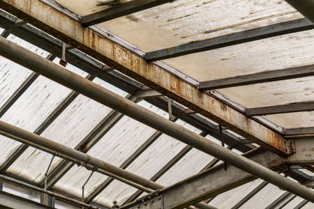 metal and glass roof of a greenhouse with pipes 