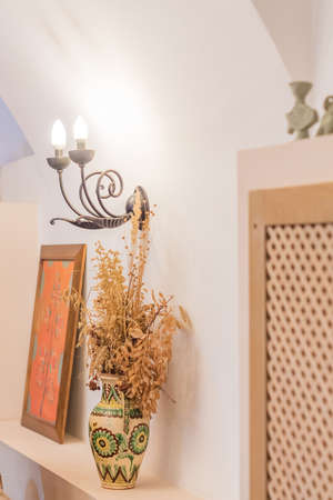 room decoration elements - clay vase with dry flowers and forged wall braceの写真素材