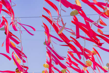 red strips of cloth hanging on a string against blue skyの写真素材