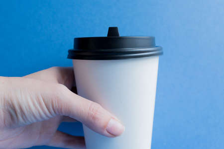 white paper kraft disposable cup for coffee with black plastic lid. coffe to go on blue background.