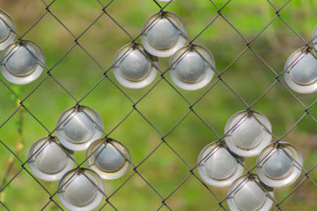 Metal chain-link fence decorated metal circles on a green grass backgroundの写真素材