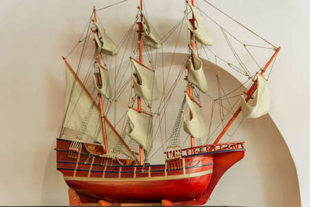Model of an old sailing ship on white wall background.